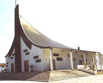 fotografia a colori della chiesa parrocchiale San Paolo Apostolo in Praia a Mare, progettata dagli architetti F. Cirillo e T. Depresbiteris, consacrata e aperta al culto l\ཇ.02.1996 (fonte: http://www.parrocchie.it/praiamare/sanpaolo/chiesa.html)