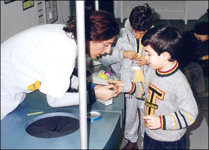 fotografia a colori di una educatrice mentre aiuta un bambino nella realizzazione del suo elaborato (autore: Gaspare Tararà)